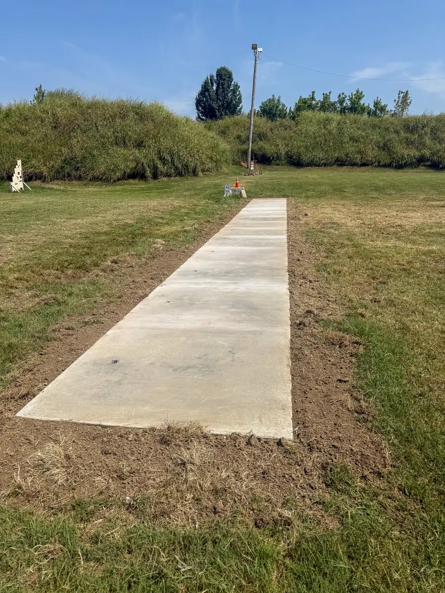 Long concrete sidewalk poured across a grassy lot
