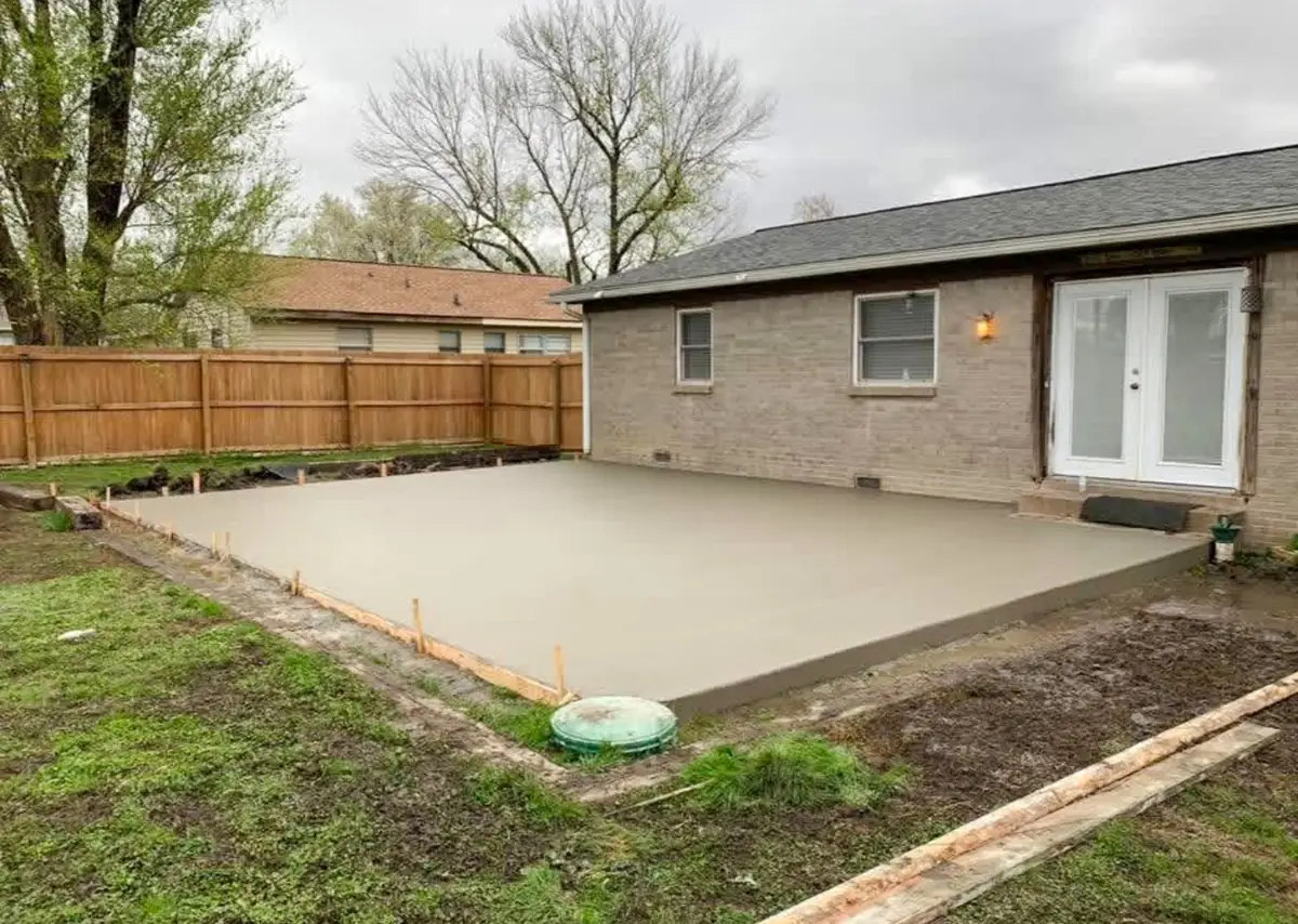 Finished concrete patio behind a brick home with French doors