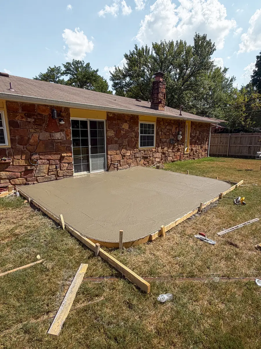 Freshly poured concrete patio slab inside wood forms
