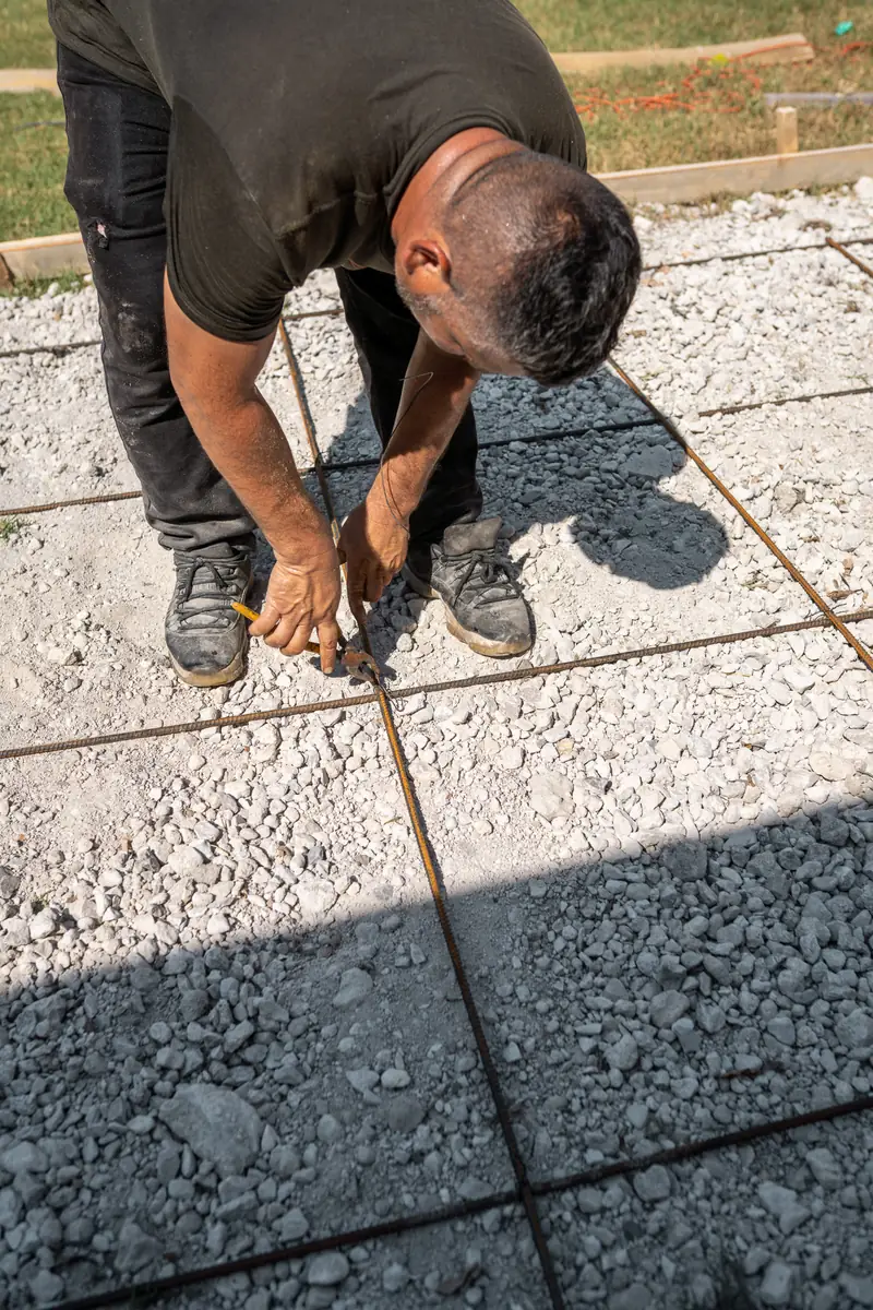 Crew member tying rebar over a compacted gravel base