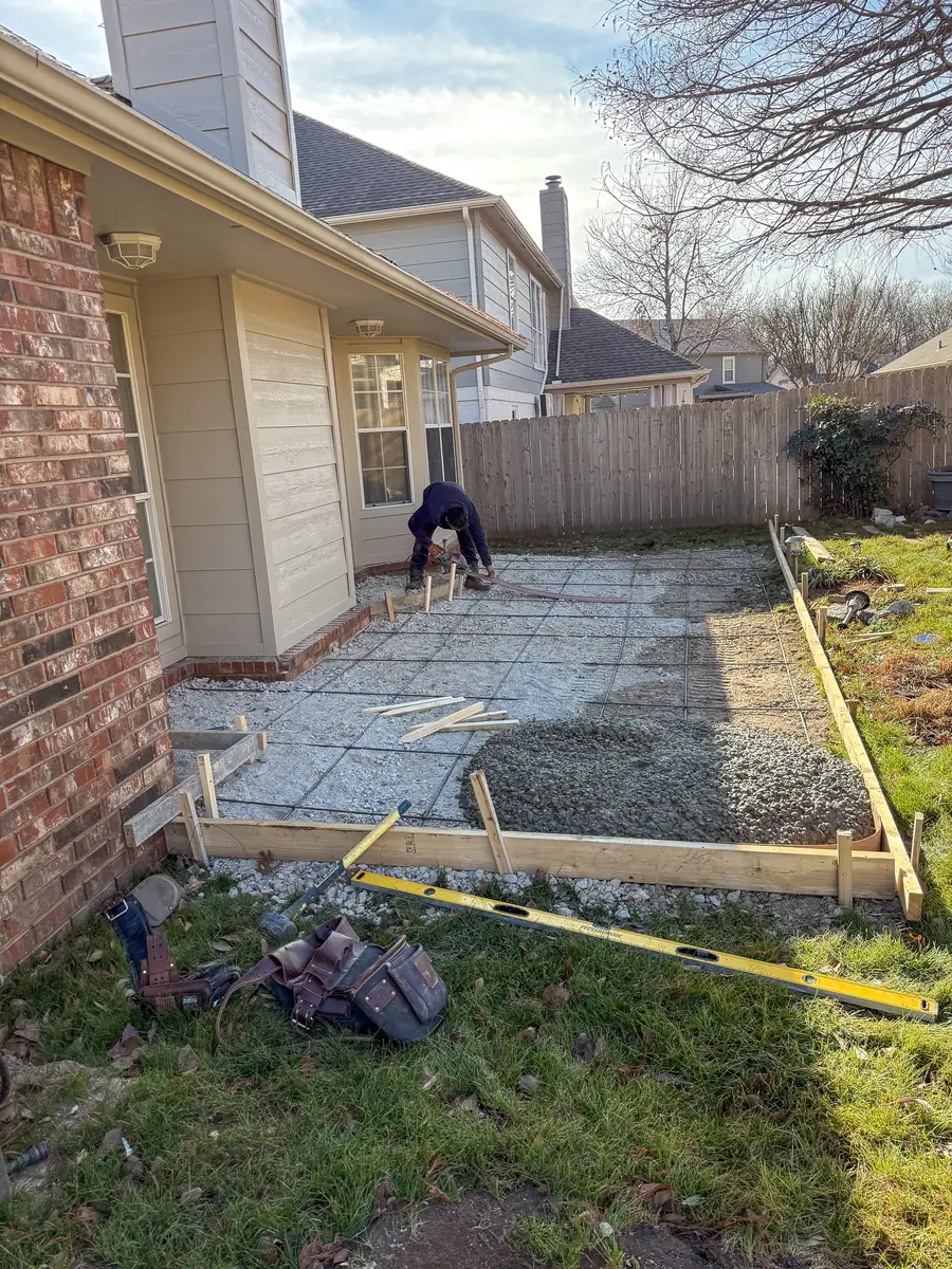 Crew prepping a side-yard concrete walkway along a brick home