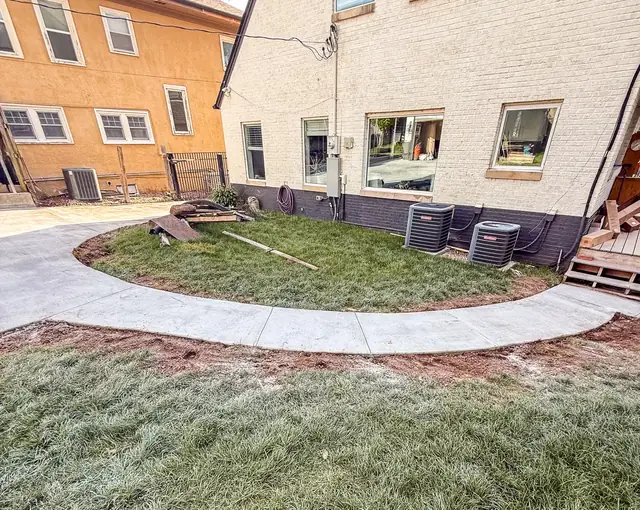 Curved concrete walkway wrapping a backyard lawn