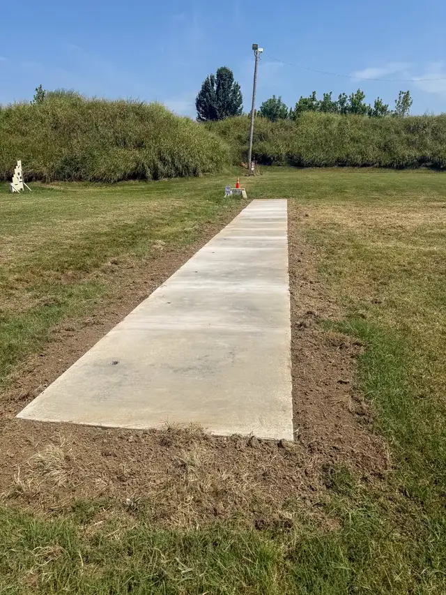 Long concrete sidewalk poured across a grassy lot