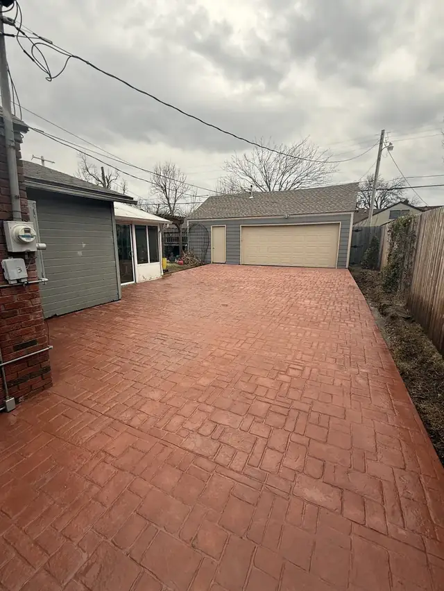 Stamped concrete driveway with brick pattern leading to a detached garage
