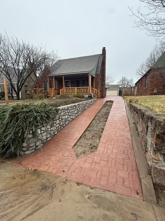 Stamped concrete ribbon driveway between stone retaining walls