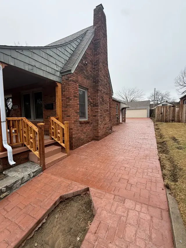Brick-stamped concrete walkway and drive wrapping a front porch
