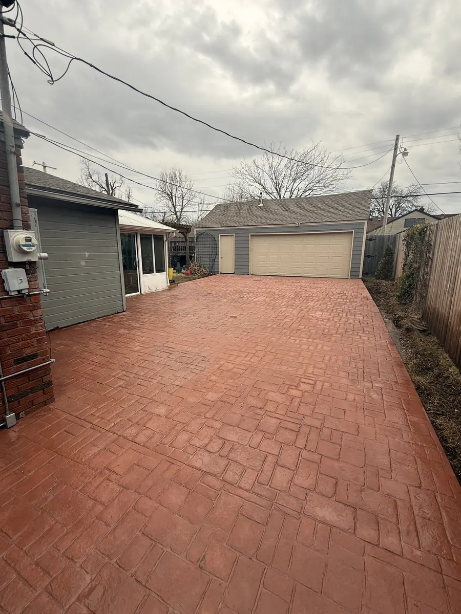 Stamped concrete driveway with brick pattern leading to a detached garage