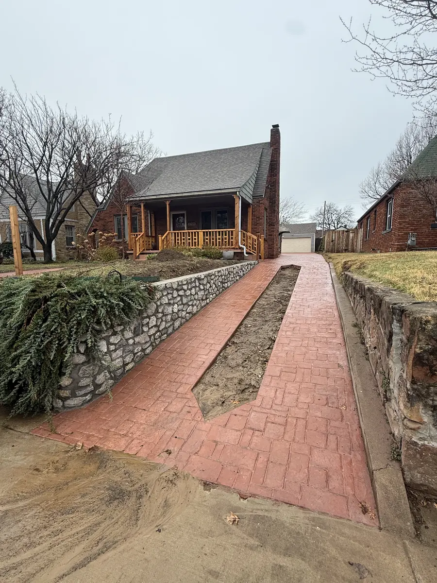 Stamped concrete ribbon driveway between stone retaining walls