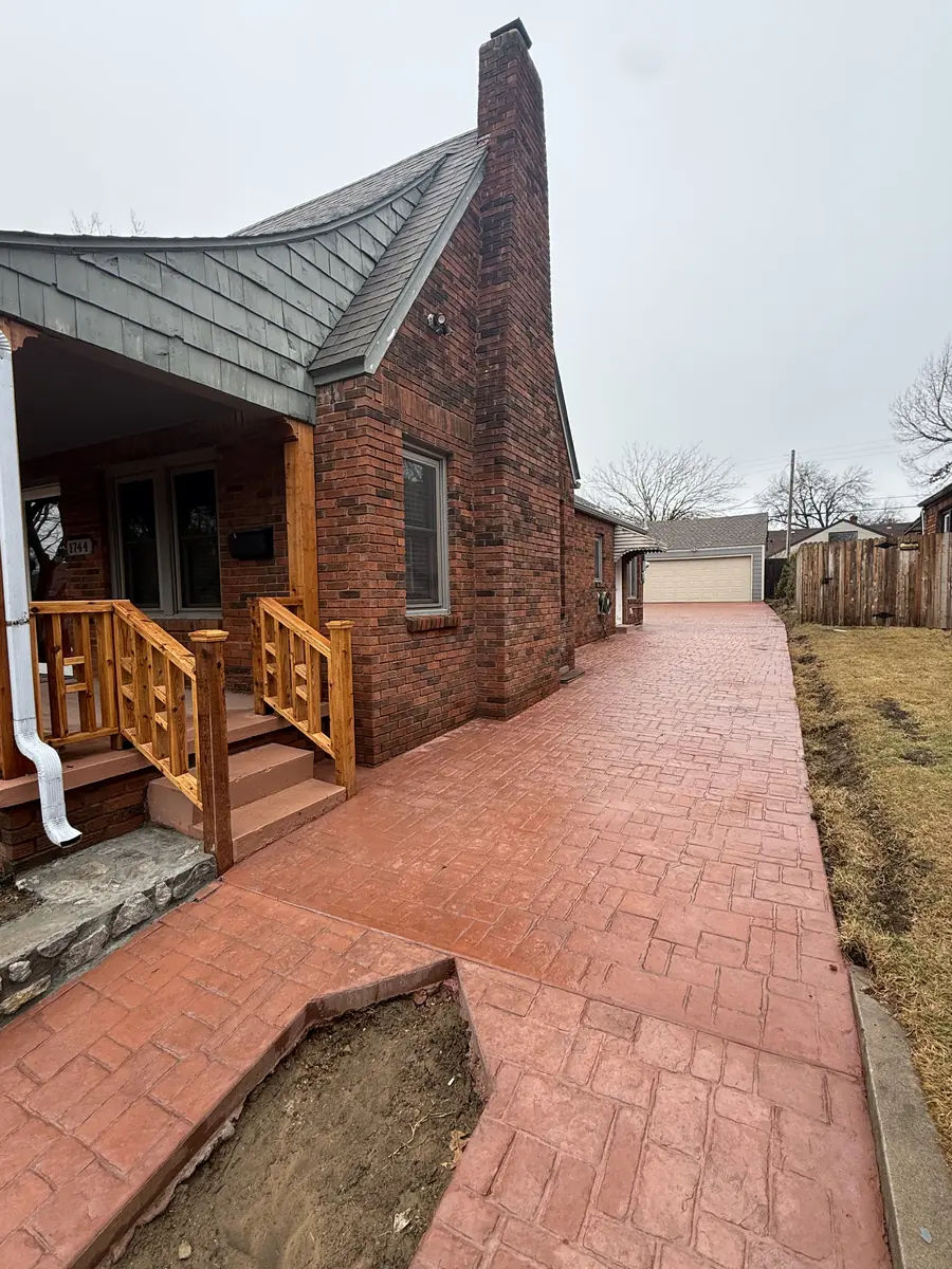 Brick-stamped concrete walkway and drive wrapping a front porch